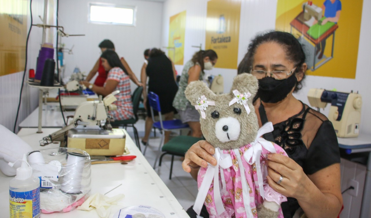 mulher segurando ursinho de pelúcia que ela produziu